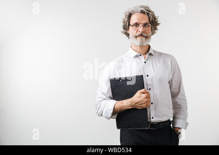 Portrait of a handsome smiling mature businessman dressed in formal wear standing isolated over white background, holding notepad Stock Photo