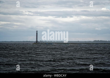 Beacon and pier on river calm after storm and strong wind. Lighthouse in the middle. Enhanced sky Stock Photo