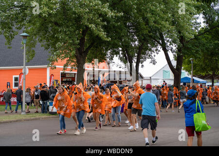 Falcon Heights, MN - August 25, 2019: Fairgoers grab Home Depot plastic rain ponchos at the booth as rain begins to pour at the Minnesota State Fair Stock Photo