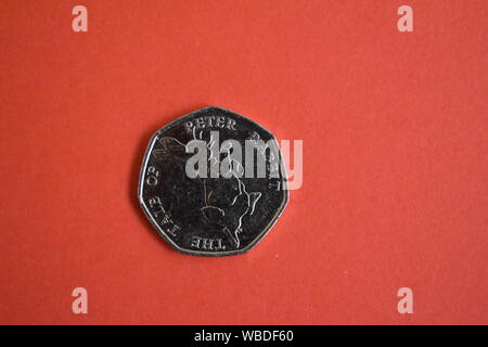 The Tales Of Peter Rabbit circulated 50p collectable coin on a dark pink background. With a picture of Peter Rabbit on the front. Stock Photo