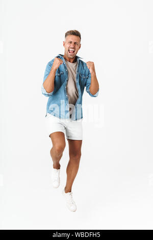 Full length photo of excited guy in denim shirt rejoicing and gesturing in triumph isolated over white background Stock Photo