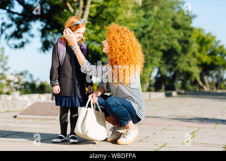 Charming red haired schoolgirl looking at her mom Stock Photo