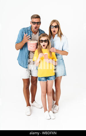 Photo of surprised family in 3D glasses holding popcorn bucket while watching movie in cinema isolated over white background Stock Photo