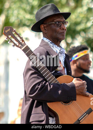 A man with a Spanish guitar, during the celebration.The main events of Notting Hill Carnival 2019 got underway, with over a million revellers hitting the streets of West London, amongst floats, masqueraders, steel bands, and sound systems. Stock Photo