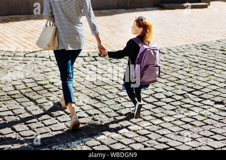 Beautiful schoolgirl holding hand of her mother Stock Photo