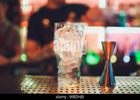 Bartender squeezing juice from fresh lime in a glass using citrus press and splashing it out making an alcoholic cocktail Stock Photo