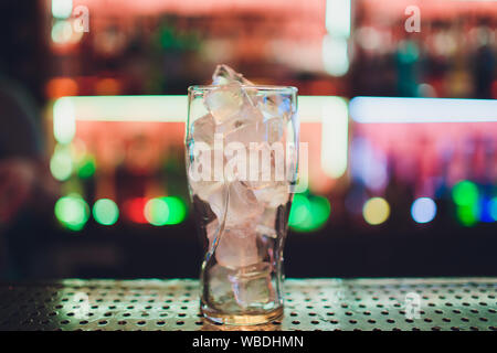 Bartender squeezing juice from fresh lime in a glass using citrus press and splashing it out making an alcoholic cocktail Stock Photo