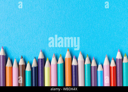 Border of colored pencils against a bright blue textured background. Back to school concept with copy space Stock Photo