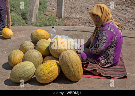 An elderly woman selling water melons on the street in Uzbekistan. Stock Photo