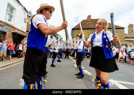 Sandwich folk and Ale Festival event in UK. Traditional folk dancers, Royal Liberty Morris side holding wooden staffs while dancing in the street. Stock Photo