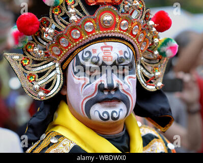 Costumed participant with elaborate traditional headdress and painted face at Bangkok’s Chinese New Year street parade poses for the camera. Stock Photo