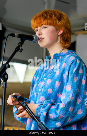 Sandwich folk and Ale Festival. Young teenage red head Caucasian women singing into microphone on stage. Woman from the Selkies folk duo. Stock Photo