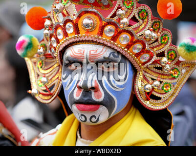 Costumed participant with elaborate traditional headdress and painted face at Bangkok’s Chinese New Year street parade poses for the camera. Stock Photo