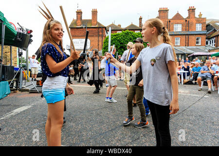 Sandwich folk and Ale Festival. Traditional morris dance outdoor workshop with people dancing in the street.Two young teenage girls dancing. Stock Photo