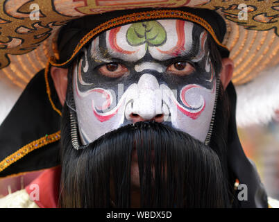 Costumed participant with traditional painted face at Bangkok’s Chinese New Year street parade poses for the camera. Stock Photo