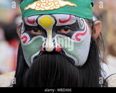 Costumed participant with traditional painted face at Bangkok’s Chinese New Year street parade poses for the camera. Stock Photo