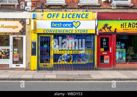 Off licence and convenience store closed and protected by metal barrier Stock Photo