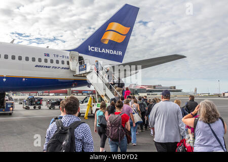Airline passengers boarding a commercial jet on the tarmac in Iceland for a vacation or a trip home.