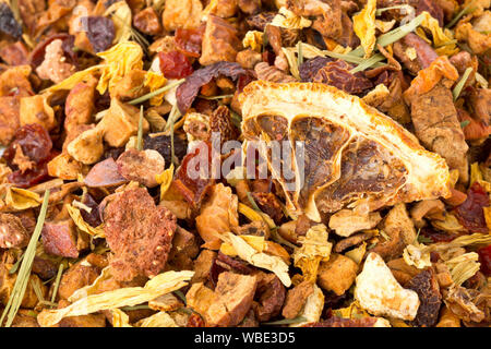 Heap of dried fruit tea infusion with oranges and strawberries mixed with tea leaves and assorted herbs close up macro with selective focus Stock Photo