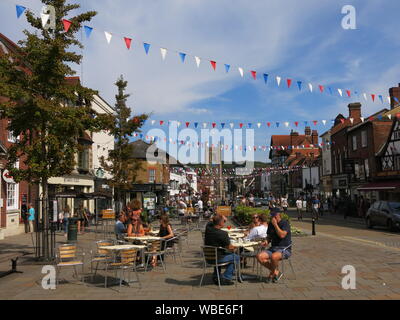 Market Place in Henley on a summer's day with bunting across the street and shoppers seated at outside tables enjoying the sunshine. Stock Photo