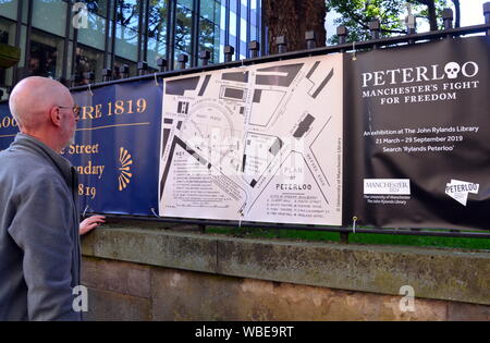 A senior man looks at a map of the Peterloo massacre on the fence of the Friend's Meeting House on Mount Street, central Manchester, At the Peterloo massacre of 1819 the cavalry charged a crowd of some 60,000 people gathered on St Peter's Fields in Manchester to demand the reform of parliamentary representation. Eighteen people were killed and hundreds injured. Stock Photo