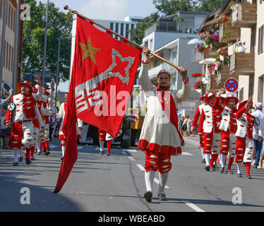Worms, Germany. 25th August 2019. Journeymen march in the parade in traditional costume. They are led by a colour guard, who carries a flag with the coat of arms of Worms. The first highlight of the 2019 Backfischfest was the big parade through the city of Worms with over 70 groups and floats. Community groups, music groups and businesses from Worms and further afield took part. Stock Photo