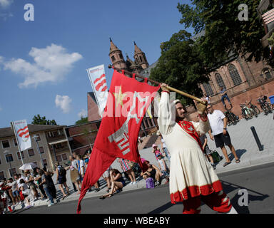 Worms, Germany. 25th August 2019. A colour guard of the journeymen marches in the parade, carrying a flag with the coat of arms of Worms. The first highlight of the 2019 Backfischfest was the big parade through the city of Worms with over 70 groups and floats. Community groups, music groups and businesses from Worms and further afield took part. Stock Photo