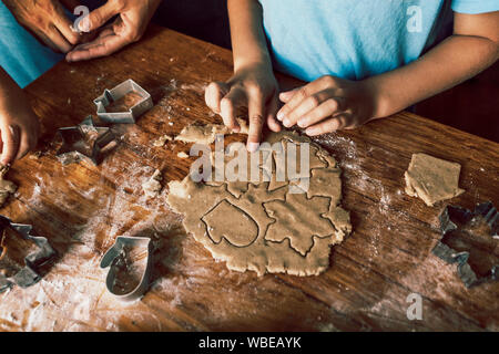 Closeup lifestyle process of cutting out figures of a Christmas tree, snowflakes and mittens for gingerbread from dough. Stock Photo