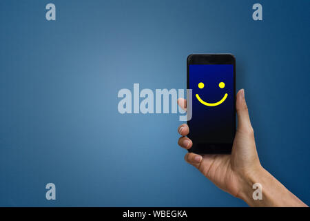Conceptual the customer responded to the digital survey. The client showing mobile phone screen with happy face. Depicts that customer is very satisfi Stock Photo