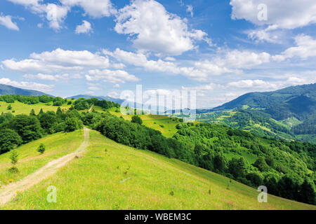 beautiful mountain landscape in summertime. footpath through forests and grassy meadow on rolling hills. ridge in the distance. amazing sunny weather Stock Photo
