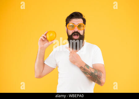 Dont panic, its organic. Bearded man pointing finger at organic orange fruit on yellow background. Hipster choosing natural organic food. The organic choice. Stock Photo
