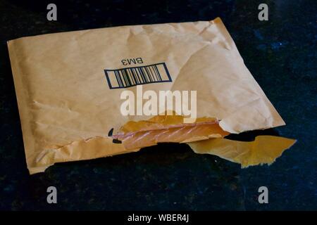 Package ripped open and sitting on top of black counter. Stock Photo