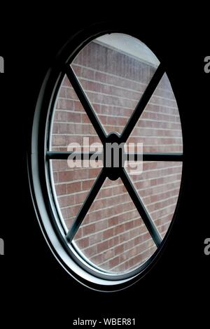 Dark room window looking out at red brick wall outside. Stock Photo
