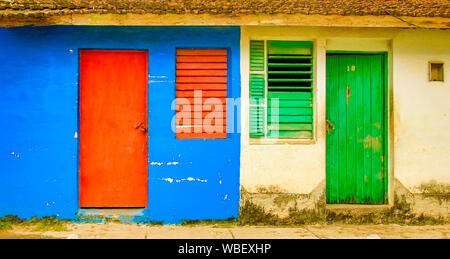 Trinidaad, Cuba Nov 26, 2017 - Red door  window on blue wall neighbors green door and window on yellow wall Stock Photo