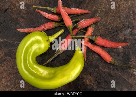 An over view photo of a green hatch pepper and small red chili peppers. Stock Photo