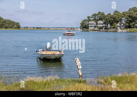 A small power boat tied up and a large power boat on a mooring in the distance in Sag Harbor, NY Stock Photo