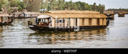 ALLEPPEY, INDIA, MAR 13, 2018: Bamboo thatched houseboat floats down the backwaters of Kerala Stock Photo