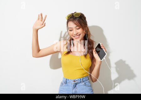 Summer lady. Beautiful asian girl singing and dancing while listening to music on white background Stock Photo