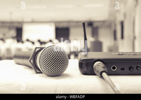 Close up old microphone wireless with box signal on the white table in business conference interior seminar meeting room and Background blur. Effects Stock Photo