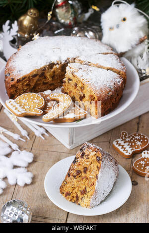 Traditional Christmas fruitcake on the background of a box with Christmas toys and fir branches. Stock Photo