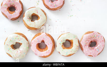 Homemade donuts decorated with colored icing and colored sugar on a light background. Stock Photo