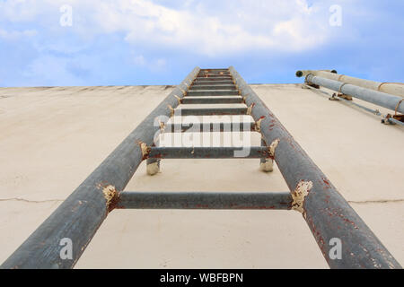 Stair old vertical industrial metal rusted to Water tank no safety rails on blue sky background with copy space Stock Photo