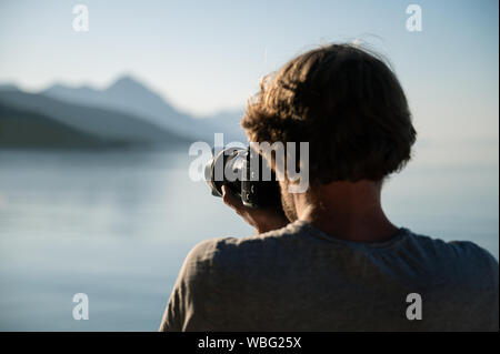 View from behind of a professional photographer taking photos of beautiful morning nature by the sea. Stock Photo
