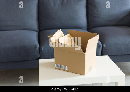 Opened cardboard over modern interior. Paper parcel opened indoors. Online shopping concept. Stock Photo