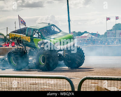 The monster truck Swamp Thing smoking its tires during the demonstration at a monster truck show at Santa Pod raceway Stock Photo