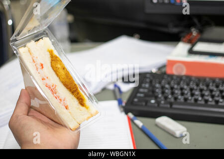 Hand holding sandwich quick lanch in the office. Homemade ham cheese sandwich. Stock Photo