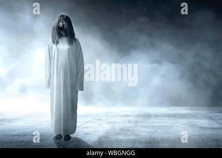 Scary ghost woman with blood and angry face standing in the dark room. Halloween concept Stock Photo