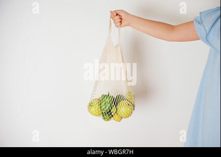 Young adult hold string bag mesh filled with colorfull fruits.Concept of natural life with zero waste or reusable eco bag for shopping, Stock Photo