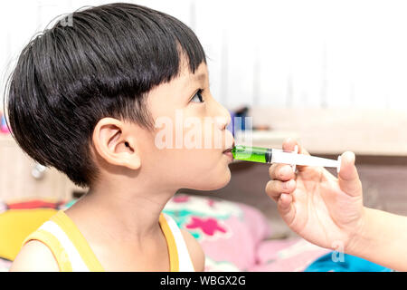 Mother giving medicine with syringe to asian little boy. Healthcare and medical concept. Stock Photo