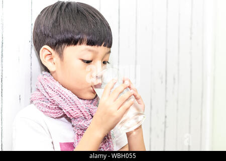 Cute asian little child drink water from glass. Portrait of boy hand holding drinking water. Stock Photo